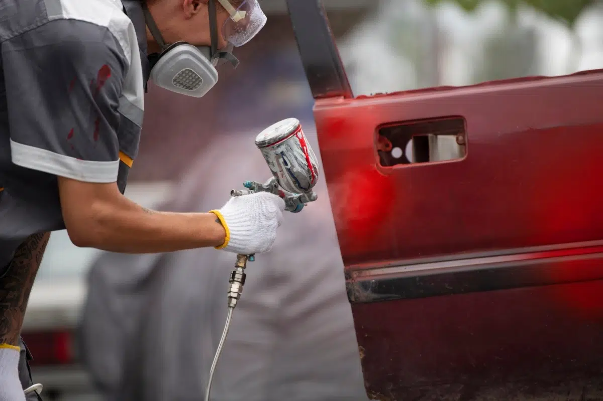 trabajador pintando puerta del coche