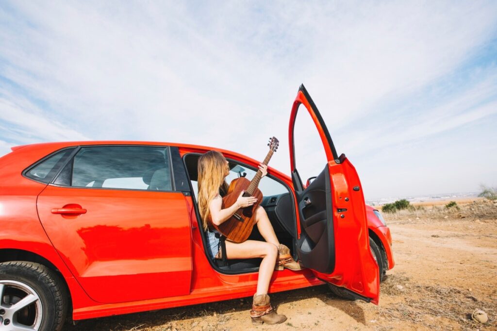mujer con guitarra en un coche